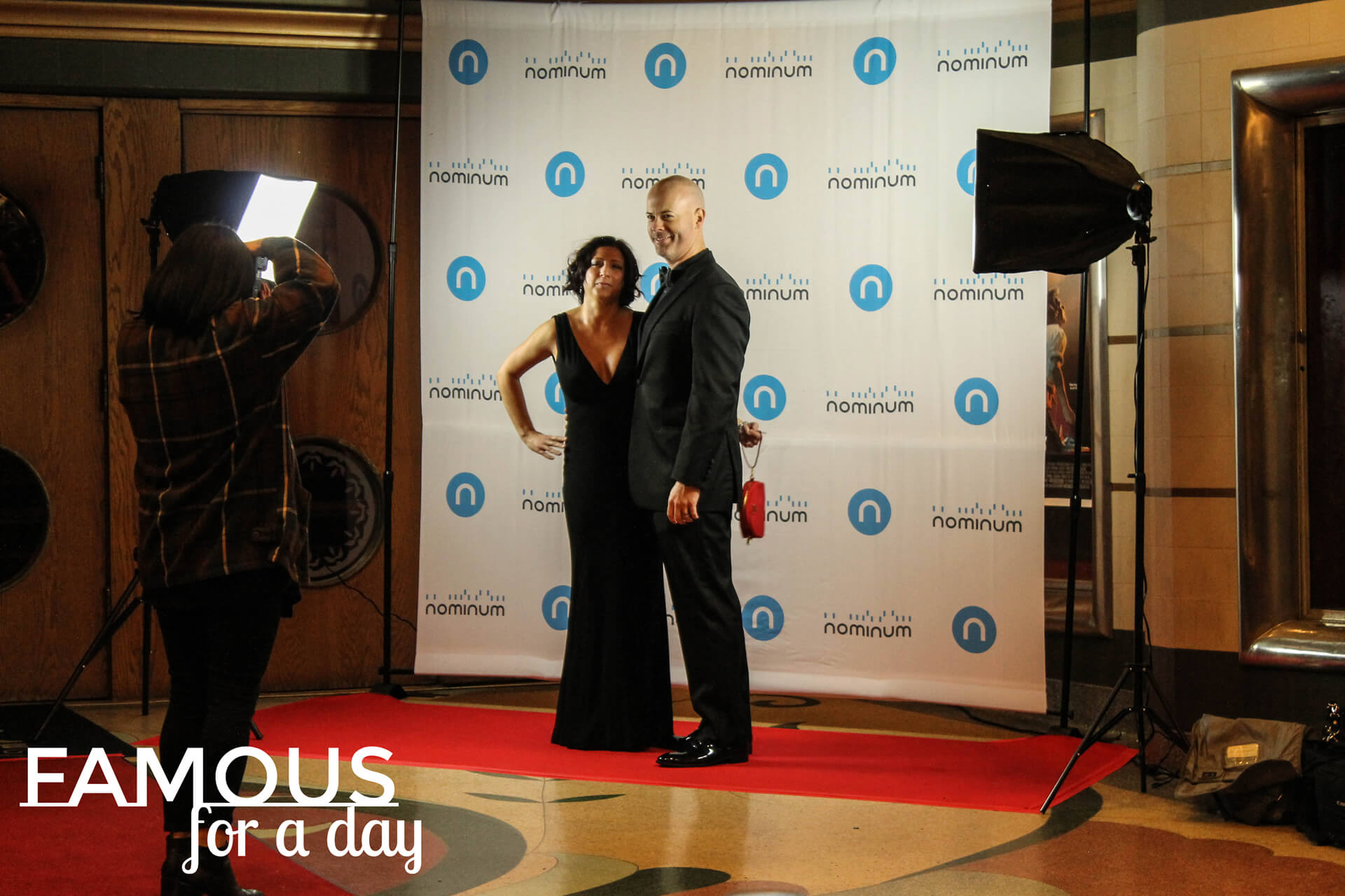 Two guests posing together in front of a branded step-and-repeat wall at an event